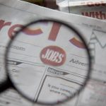 Newspapers being examined closely with a magnifying glass