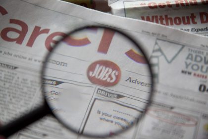 Newspapers being examined closely with a magnifying glass